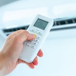 Adjusting the temperature of an air conditioner in a room or home using a remote controller for precise climate control.