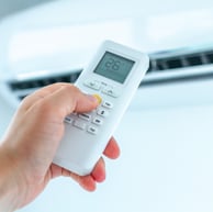 Adjusting the temperature of an air conditioner in a room or home using a remote controller for precise climate control.