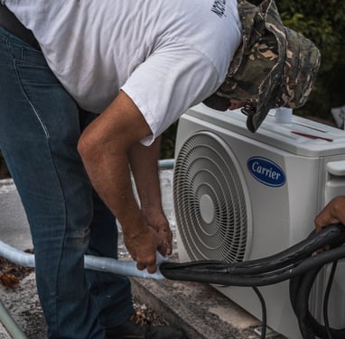 An AC technician joining the pipes of an ac unit together using adhesive tape, ensuring a tight and secure connection.